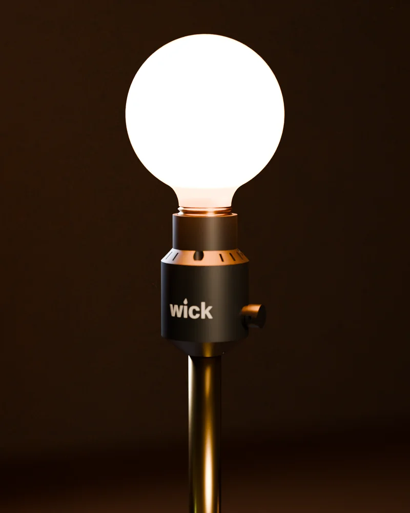 A walnut and brass table lamp with a bare amber globe on a black wick socket